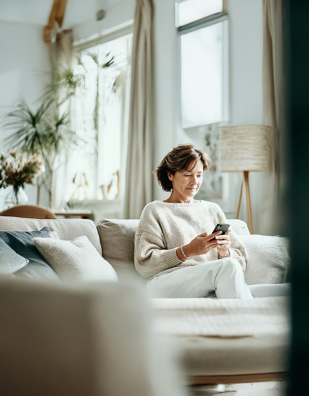 Frau mit Handy auf Sofa
