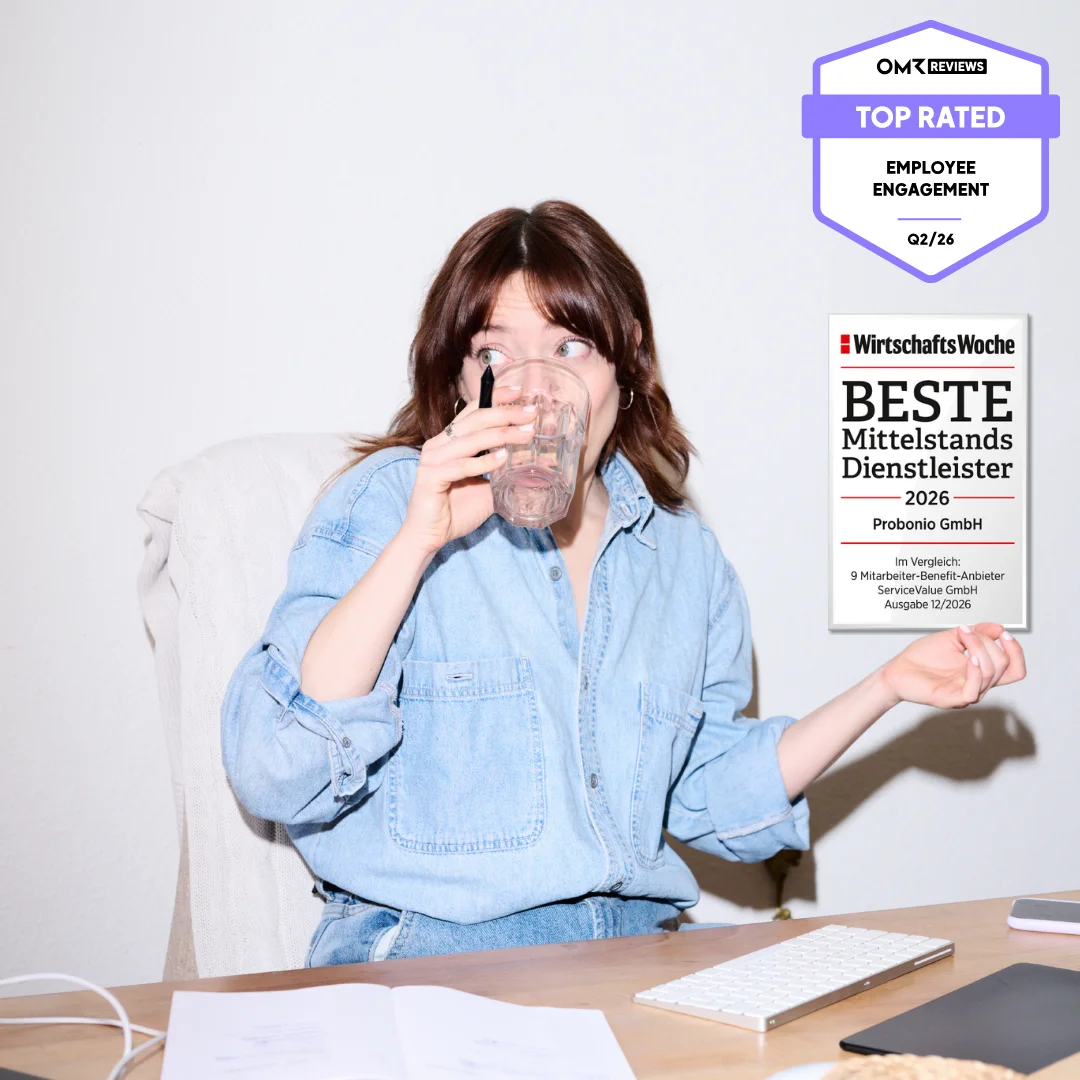 Person sitzt am Schreibtisch, trinkt aus einem Glas und schaut überrascht zur Seite; im Bild ist ein „Top Rated Employee Engagement“-Badge von OMR Reviews (Q2/26) und ein Badge von Beste Mittelstandsdienstleister 2026eingeblendet.
