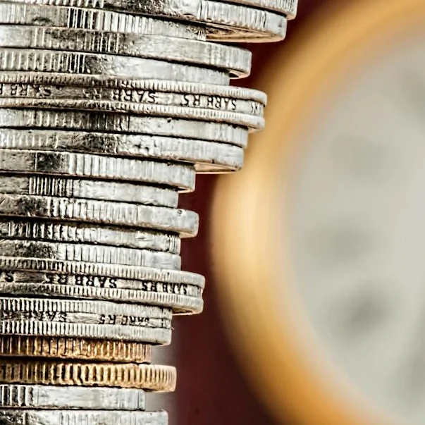 Turm aus Euromünzen mit Wanduhr im Hintergrund