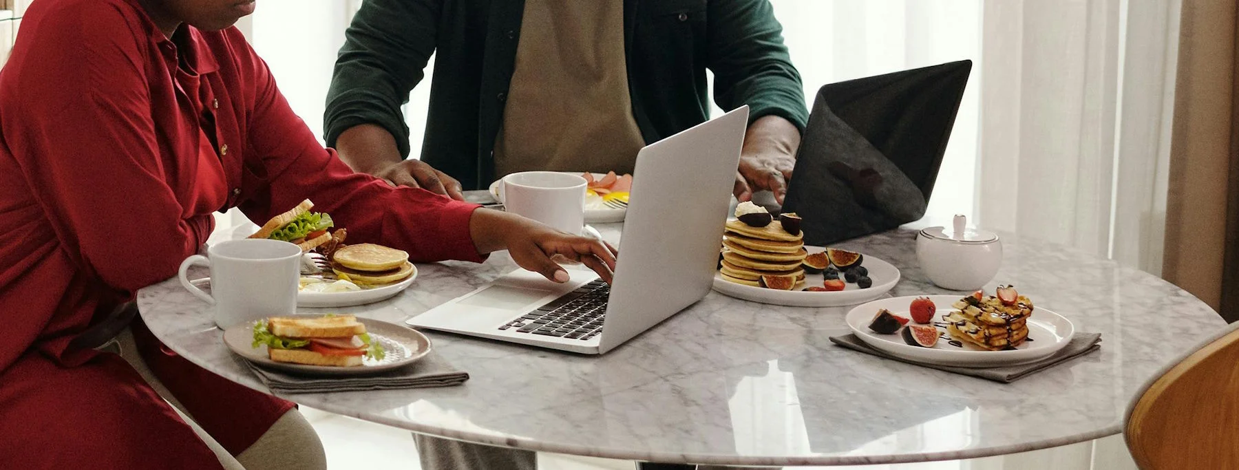 Mitarbeiter mit Essen und Laptops am Tisch