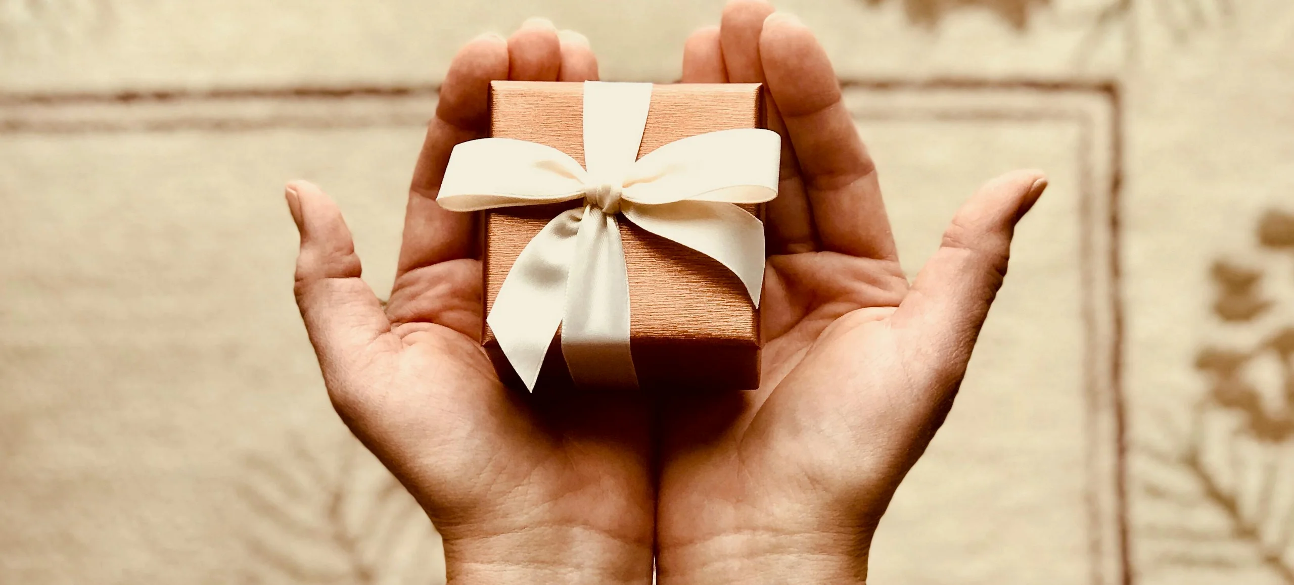 Steuerfreie Sachbezüge Minijob Ein kleines Geschenk liegt in zwei geöffneten Händen.